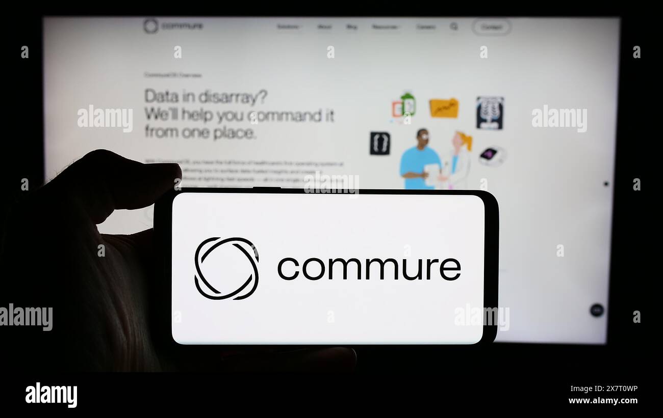 Personne tenant le téléphone portable avec le logo de la société américaine de logiciels de santé Commure Inc. devant la page Web de l'entreprise. Concentrez-vous sur l'affichage du téléphone. Banque D'Images