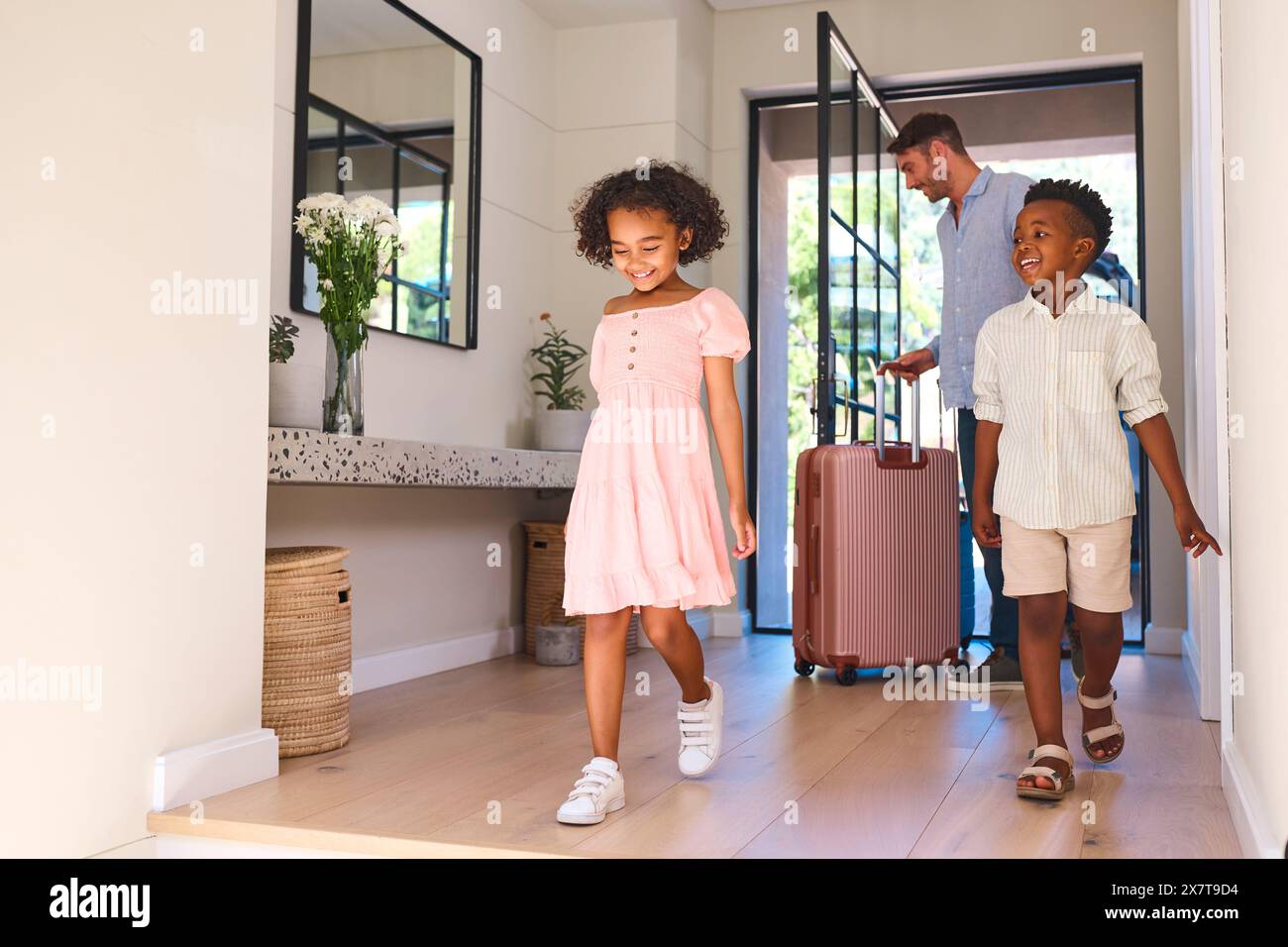 Famille multiraciale avec père et enfants arrivant dans la maison ou l'appartement pour les vacances d'été Banque D'Images