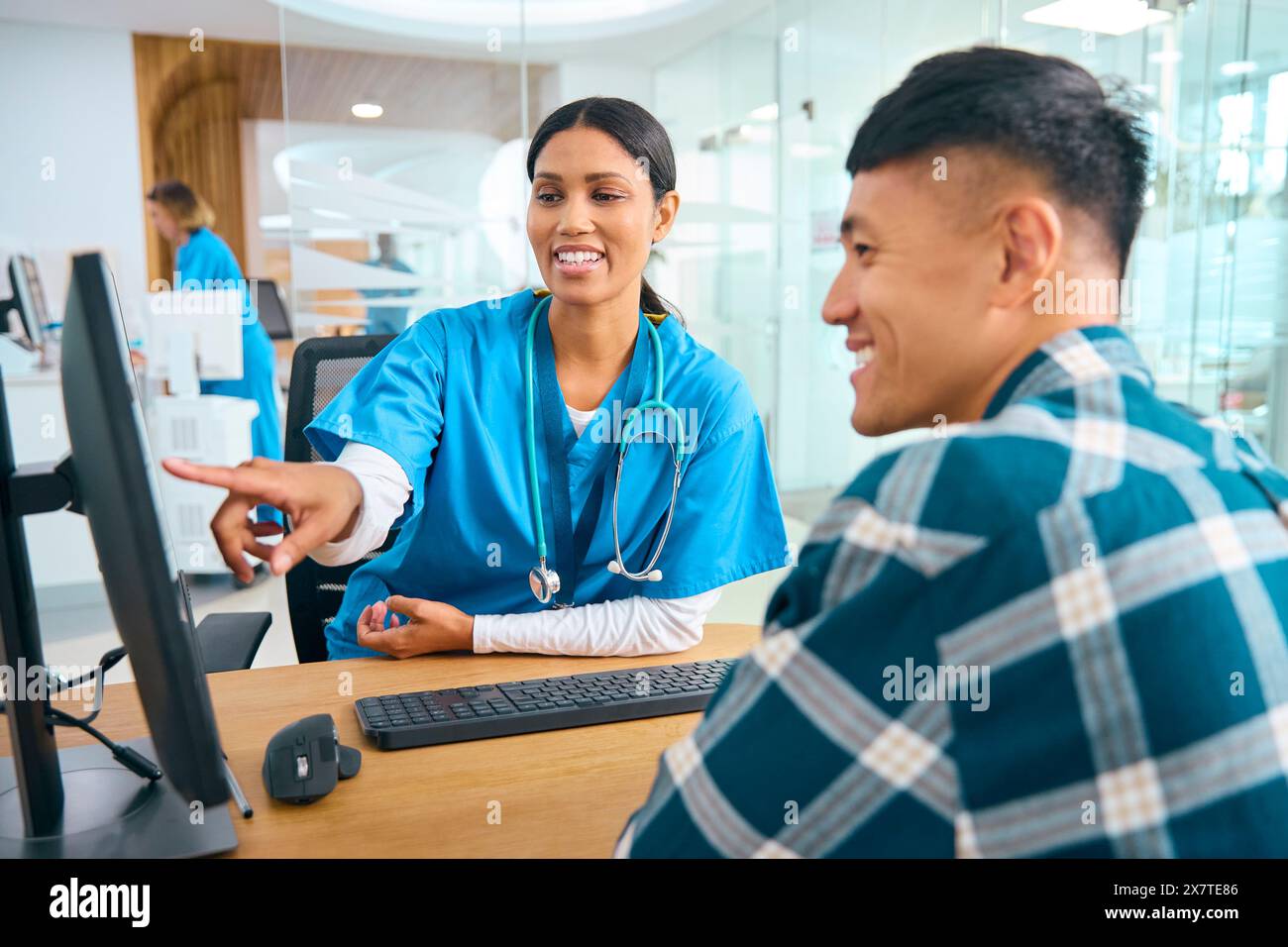 Infirmière ou médecin portant des gommages au rendez-vous de l'hôpital avec un patient masculin regardant l'ordinateur Banque D'Images