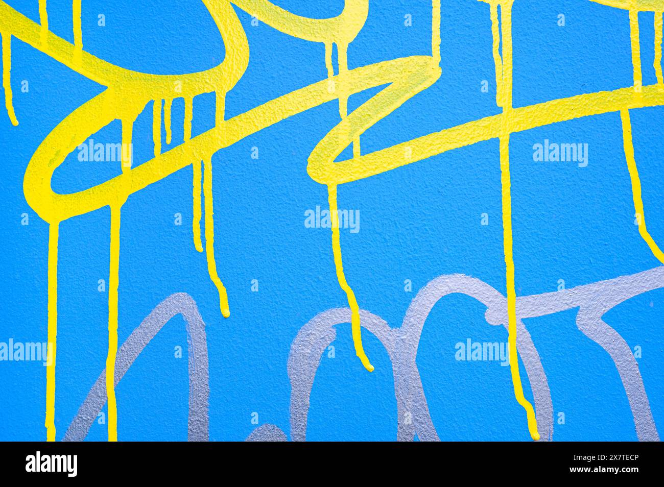 Détail de graffitis jaunes et argentés sur un mur bleu Banque D'Images