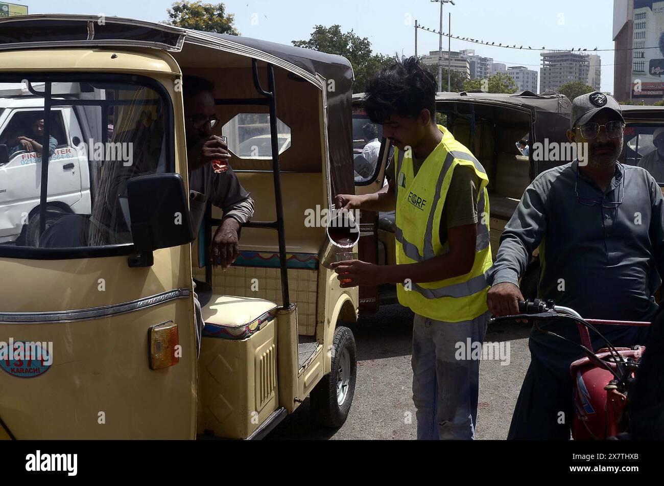 Les gens étanchent leur soif avec du jus de fruits frais pour battre la chaleur du soleil brûlant pendant le temps chaud de la saison estivale, dans un camp de secours du coup de chaleur organisé par social Organization, à proximité du bâtiment de l'Assemblée du Sindh à Karachi le mardi 21 mai 2024. Banque D'Images