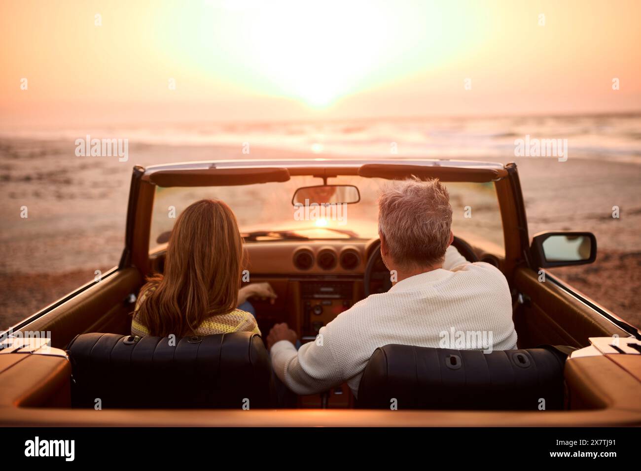 Vue arrière du couple senior retraité en vacances dans la voiture de sport classique à Beach Watching Sunrise Banque D'Images