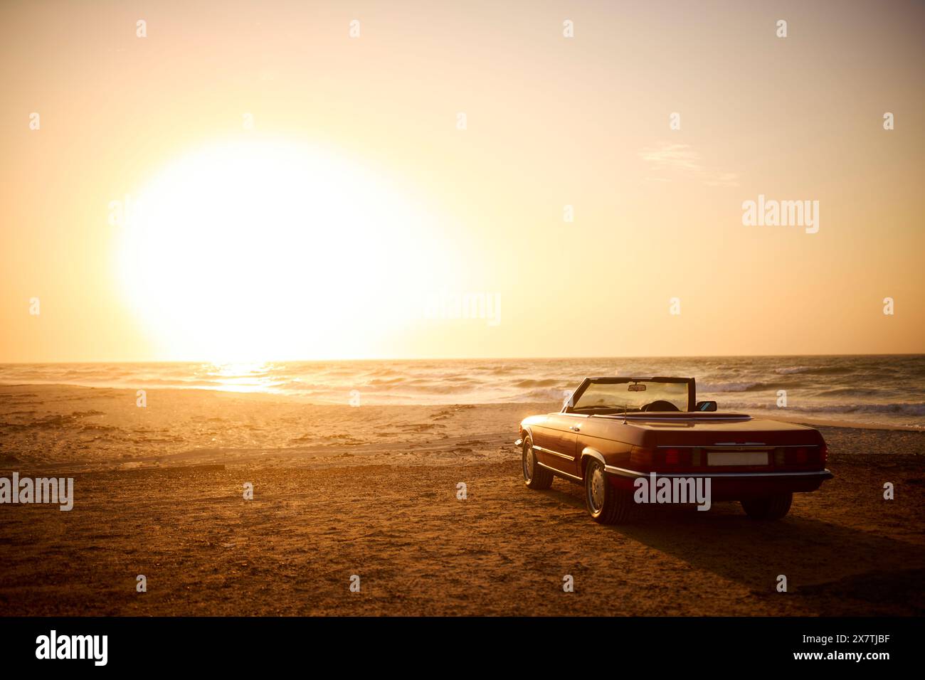 Voiture de sport décapotable classique sur le rivage de la plage au lever du soleil Banque D'Images