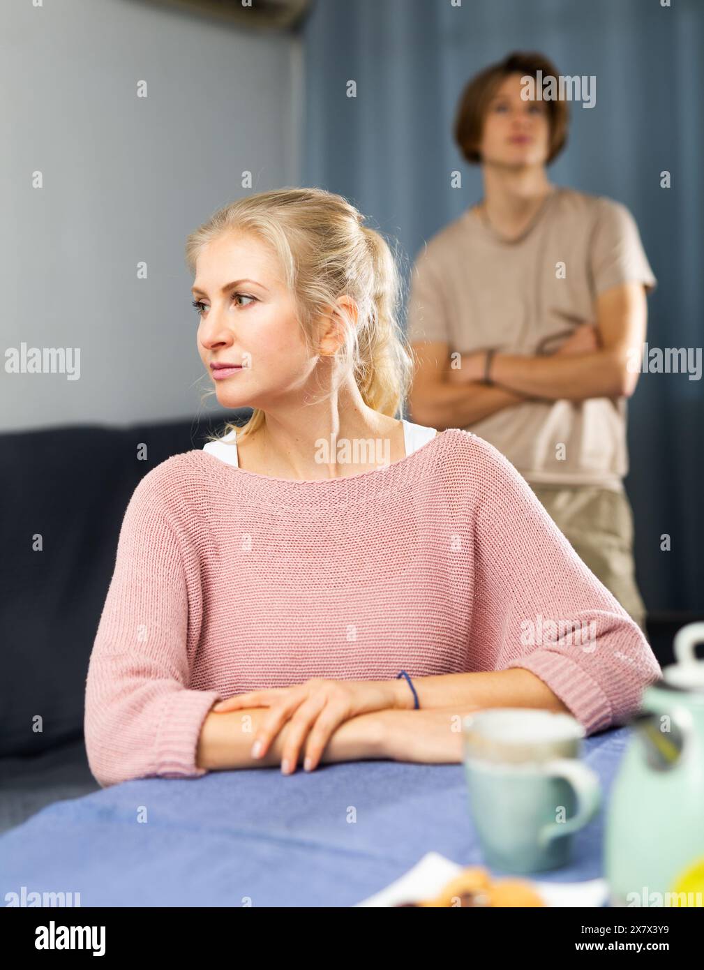 Femme contrariée assise à la table dans la cuisine Banque D'Images