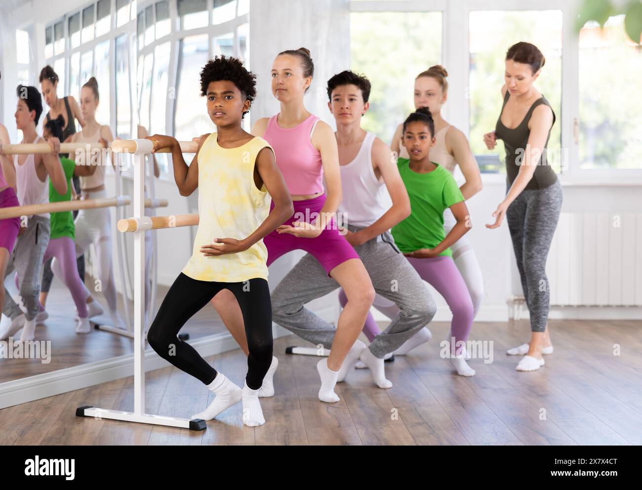 Adolescent afro-américain maîtrisant demi-plie à la barre au cours de ballet Banque D'Images