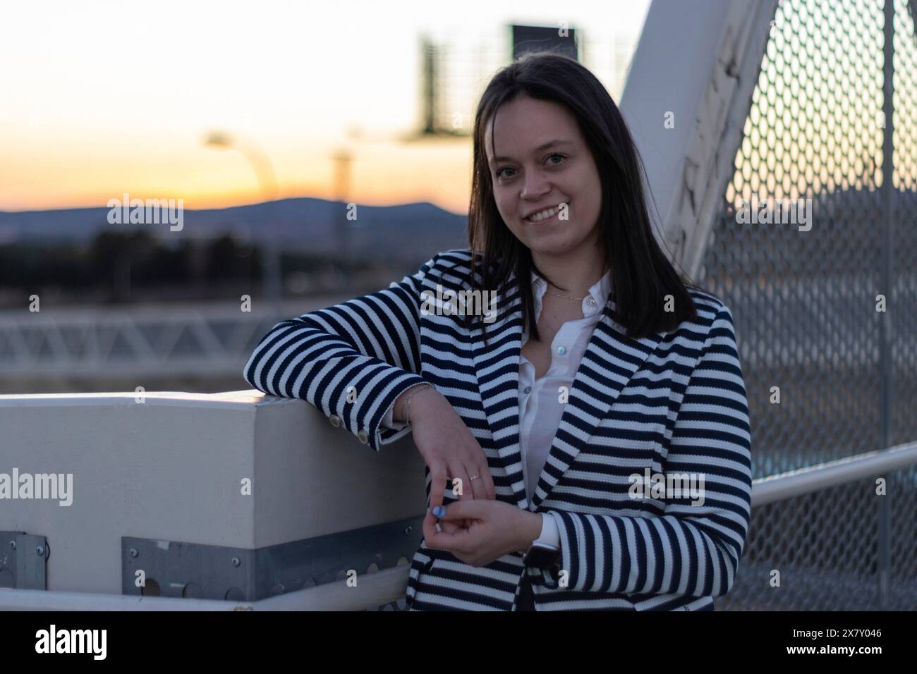 Portrait de fille souriante avec les bras croisés sur un pont dans la ville. Jeune femme souriante debout les bras croisés sur un pont Banque D'Images