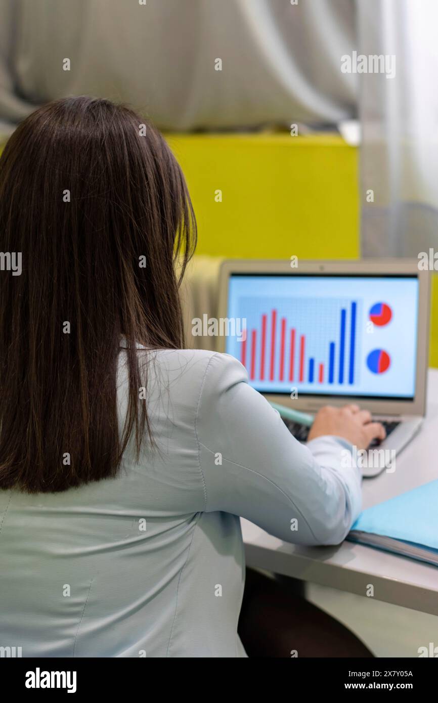 Femme d'affaires anonyme analysant des rapports d'affaires statistiques sur son PC au Bureau, un gros plan vertical Banque D'Images