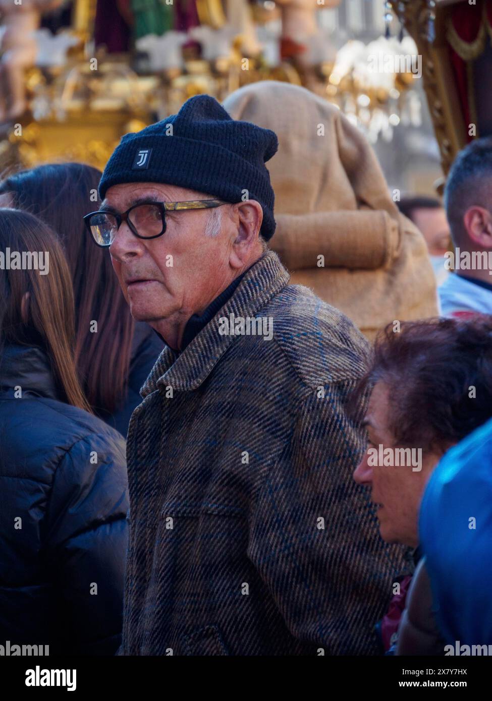 Un homme plus âgé avec des lunettes et un chapeau noir dans une foule, faisant partie d'une procession en plein air, Catane, italie, 3 février 2024, 3 jours fête Saint Agatha Banque D'Images