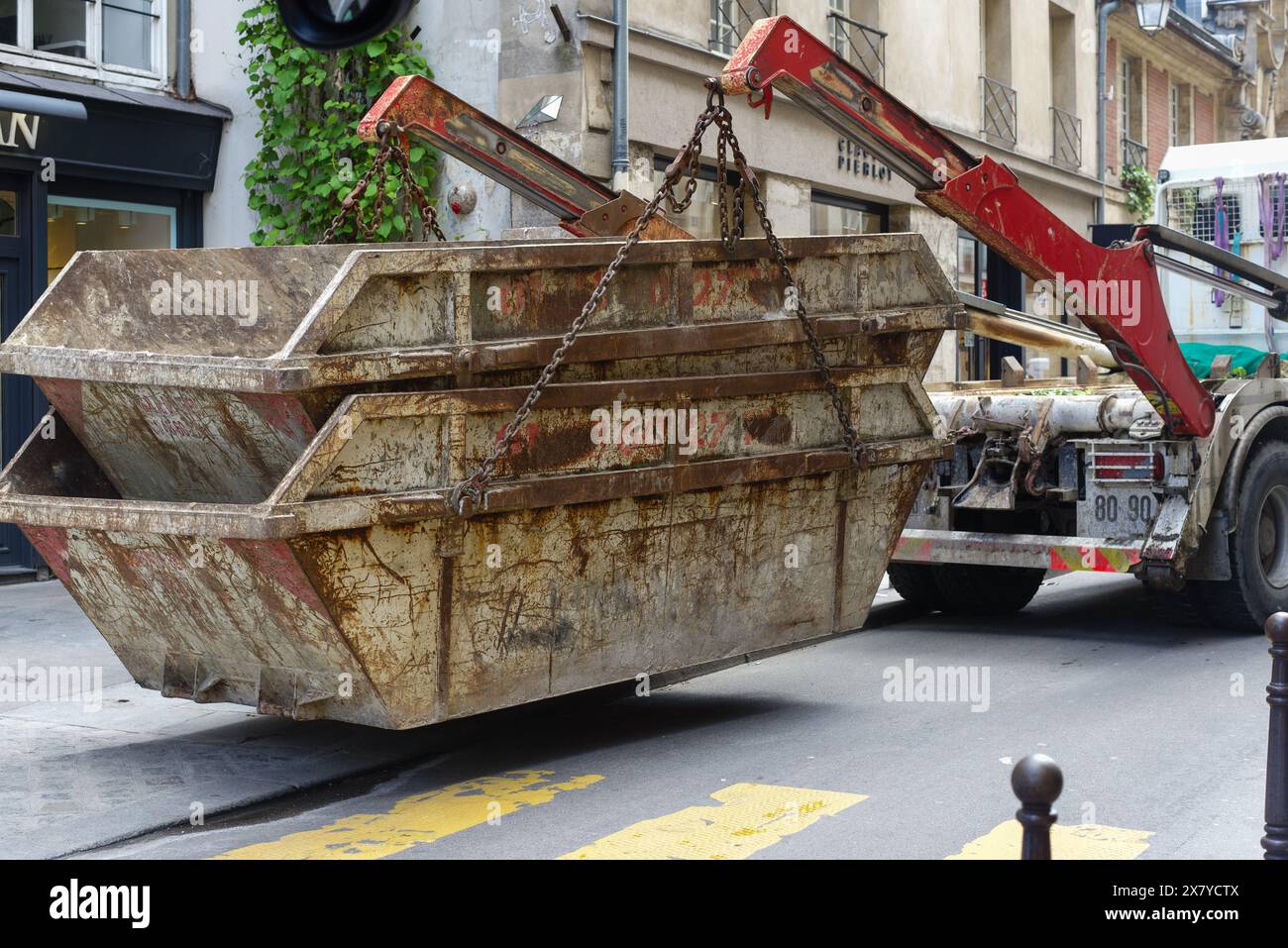 Des bennes à ordures métalliques industrielles sont placées dans une rue parisienne Banque D'Images