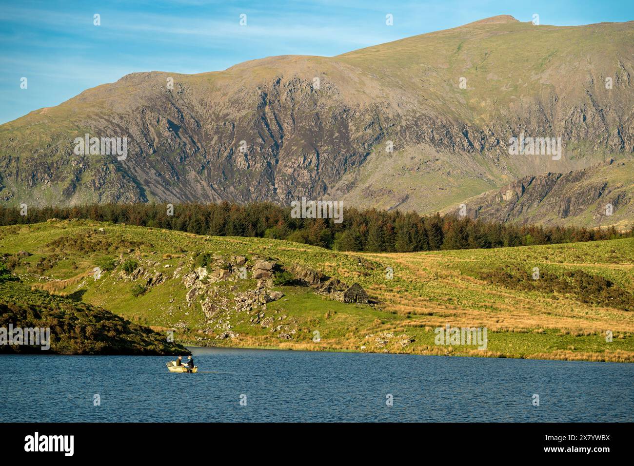 Pêcheurs à la ligne pêchant depuis un bateau sur Llyn Dywarchen dans le parc national d'Eryri, au pays de Galles avec Yr Wyddfa au loin. Banque D'Images