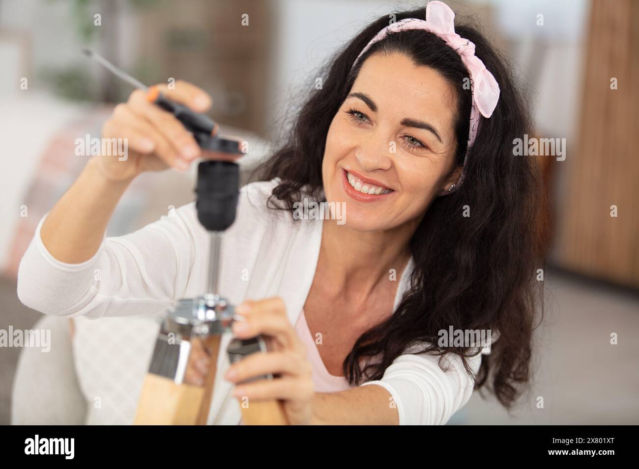 femme mature assemblant une lampe dans sa maison Banque D'Images