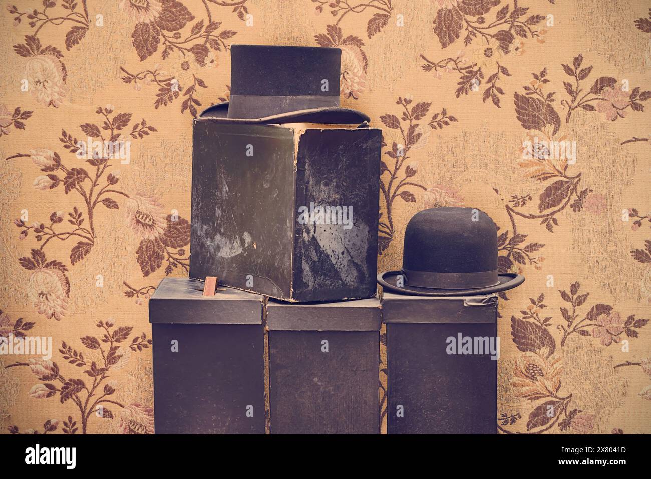 Image de style rétro de chapeaux de gentleman noir vintage avec des boîtes altérées devant le vieux papier peint Banque D'Images