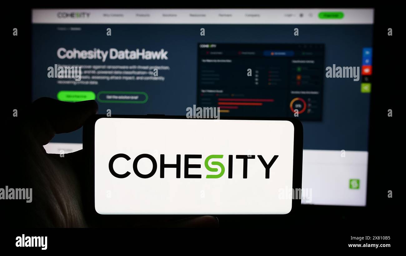 Personne tenant le téléphone portable avec le logo de la société de gestion de données américaine Cohesity Inc devant la page Web de l'entreprise. Concentrez-vous sur l'affichage du téléphone. Banque D'Images
