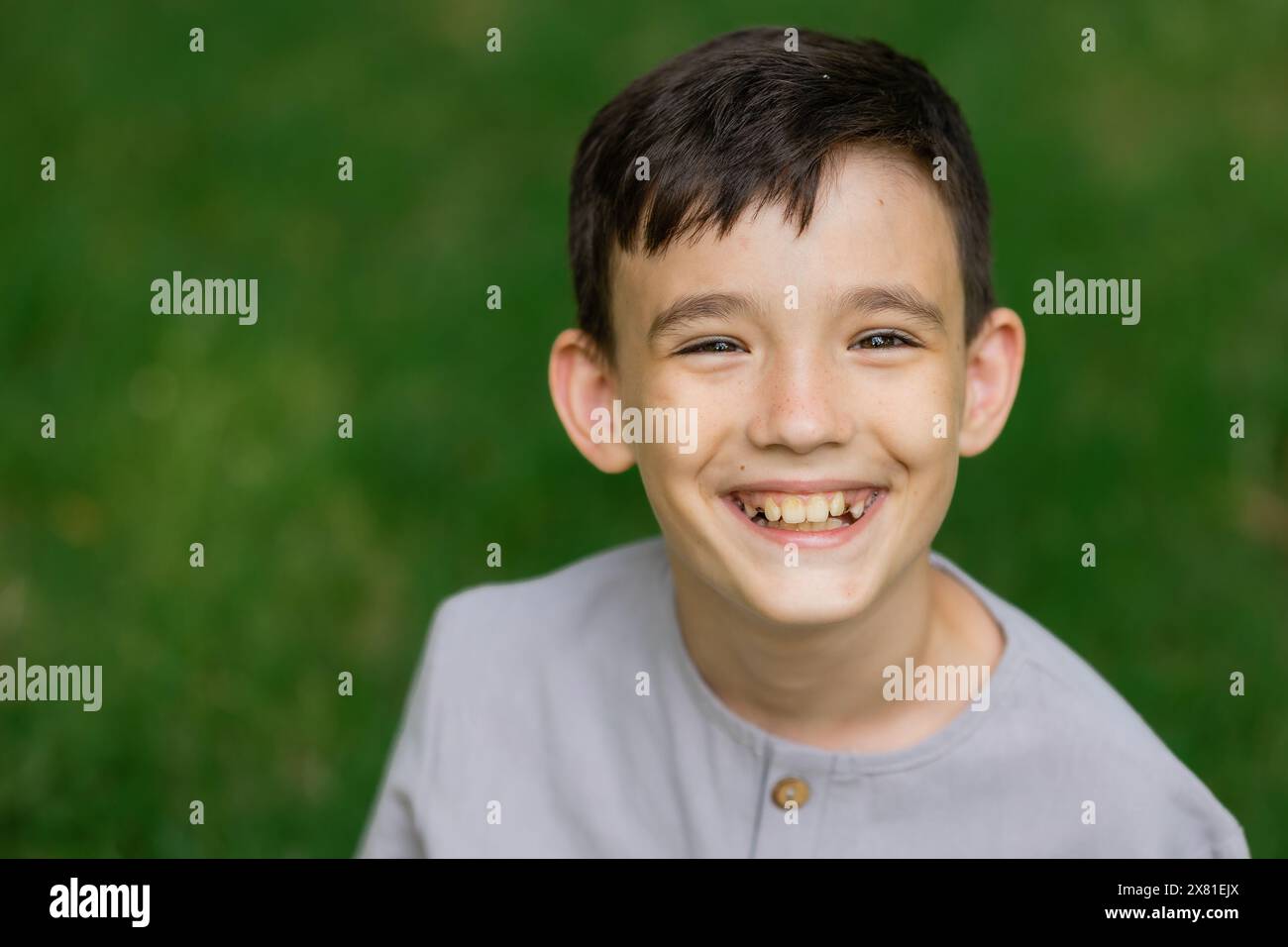 Portrait d'un petit garçon sur une pelouse verte riant, regardant la caméra,. Photo de haute qualité Banque D'Images