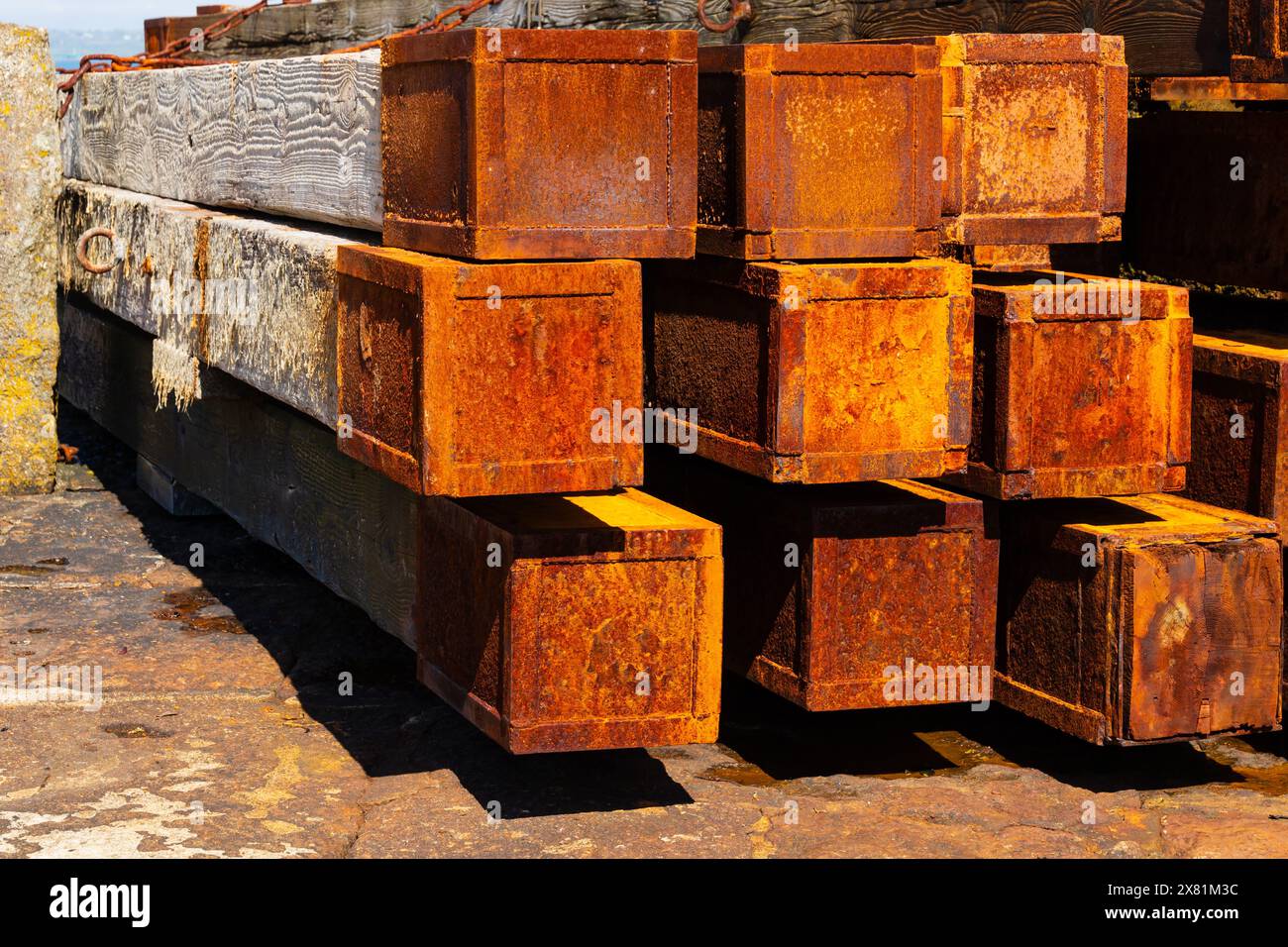 Planches de bois recouvertes d'acier rouillé utilisées comme défenses maritimes à l'entrée du port. Le pittoresque village de pêcheurs de Mousehole, Cornouailles, West Country, E. Banque D'Images