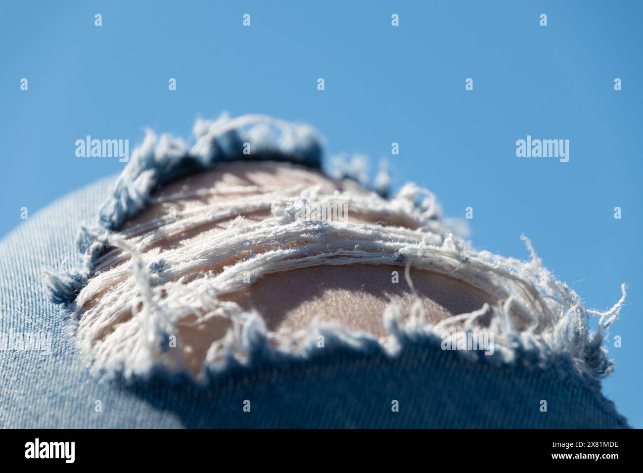 Jambes en Jean déchiré contre un ciel bleu. Fond d'été. Banque D'Images