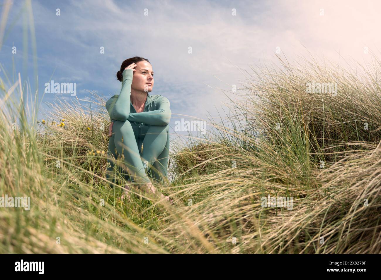 Femme sportive assise dans les dunes de sable relaxant et se reposant. Banque D'Images