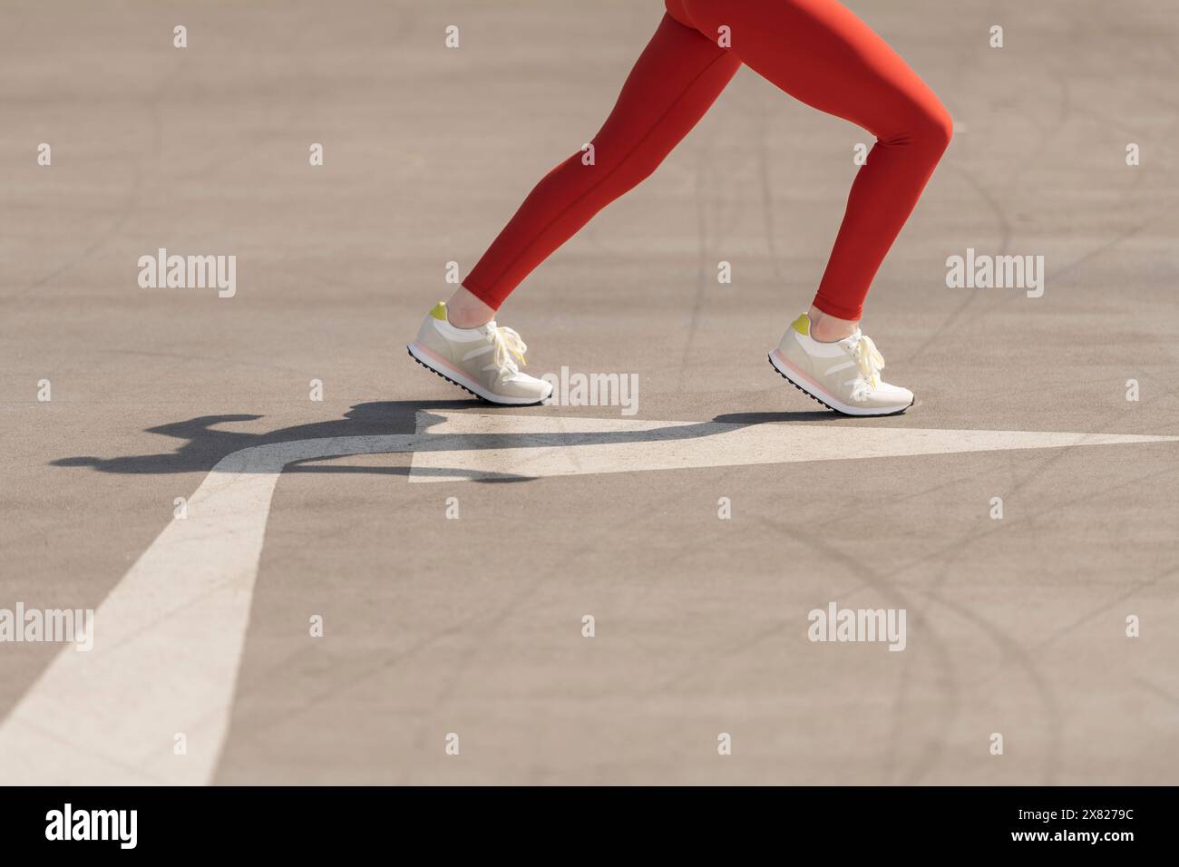 gros plan, vue à angle bas de la femme sportive courir sur la route goudronnée avec flèche Banque D'Images