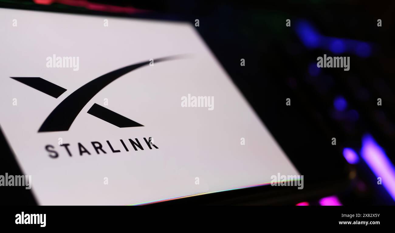 Viersen, Allemagne - 9 mai. 2024 : gros plan de smartphone avec lettrage logo de la constellation satellite Starlink sur clavier d'ordinateur Banque D'Images