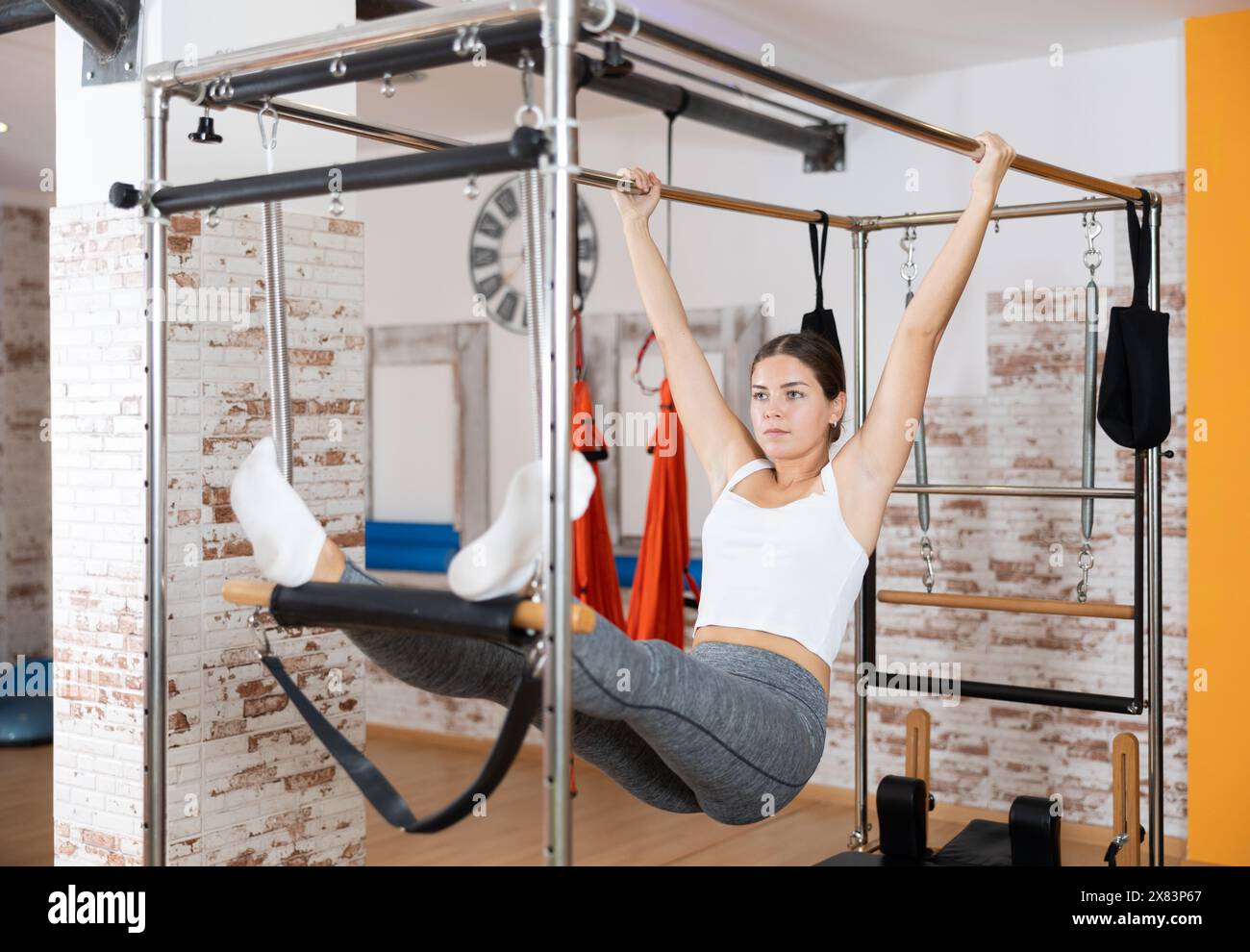 Fille visiteur effectue des exercices en position suspendue sur la table de trapèze Pilates combinée. Banque D'Images