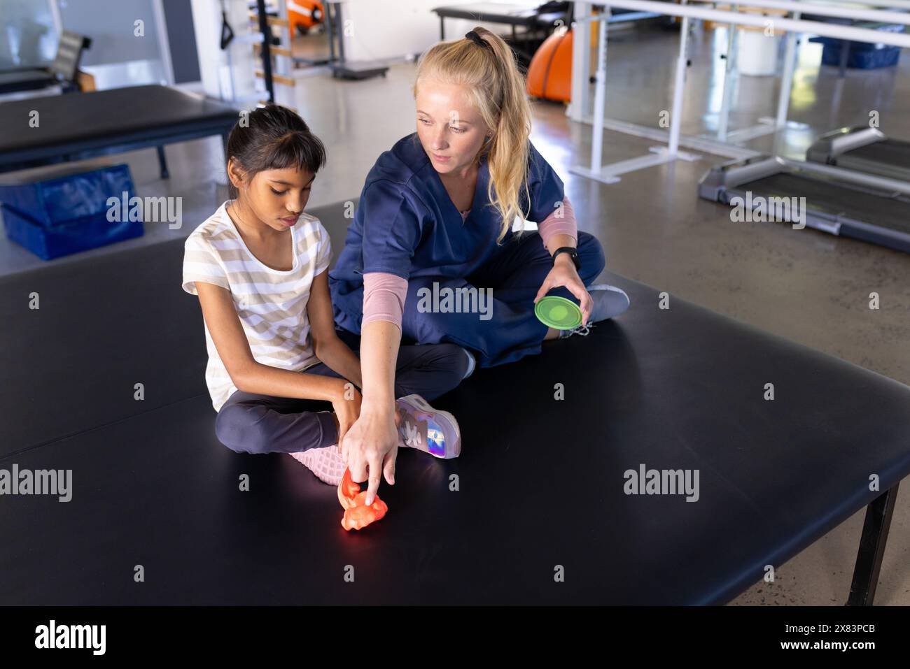 Une thérapeute féminine caucasienne traite un enfant biracial atteint de paralysie cérébrale au centre de réadaptation Banque D'Images