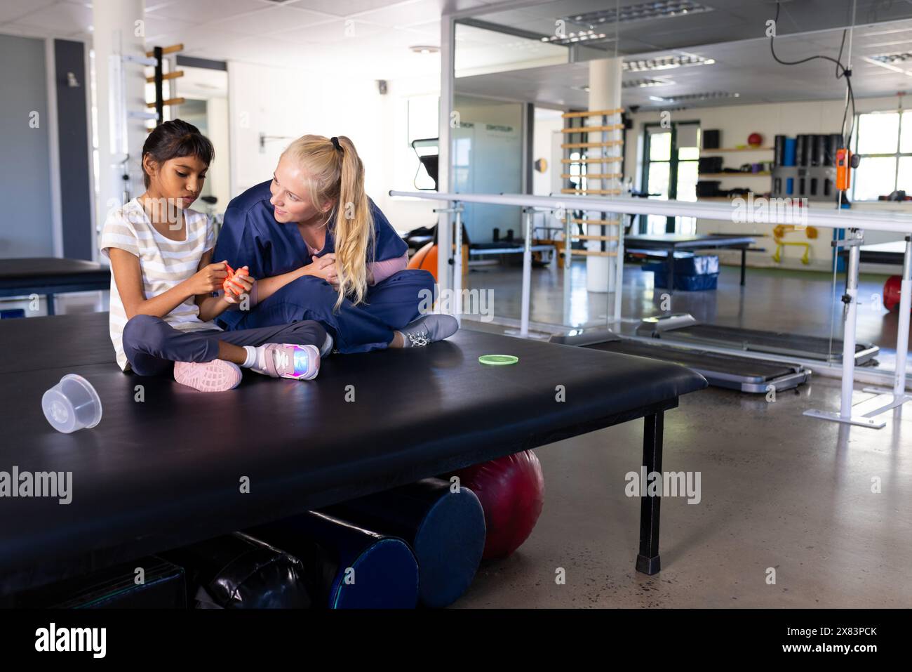 Thérapeute féminine caucasienne exerçant avec un enfant biracial atteint de paralysie cérébrale au centre de réadaptation Banque D'Images