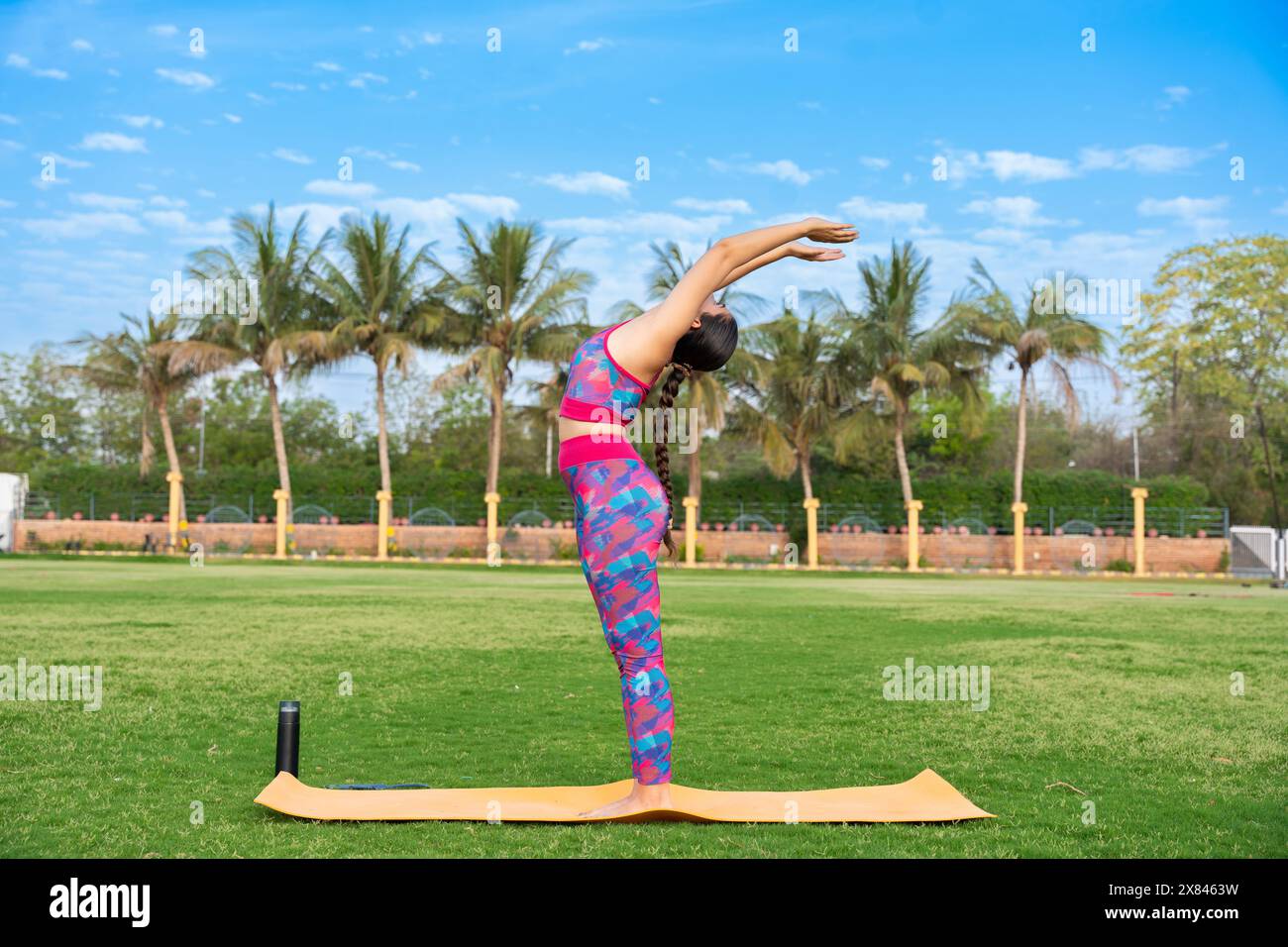 Fit jeune fille indienne faisant Surya Namaskar ou Sun Salutation yoga pose dans son jardin. exercice, entraînement, méditation, bien-être, santé mentale, journée du yoga Banque D'Images