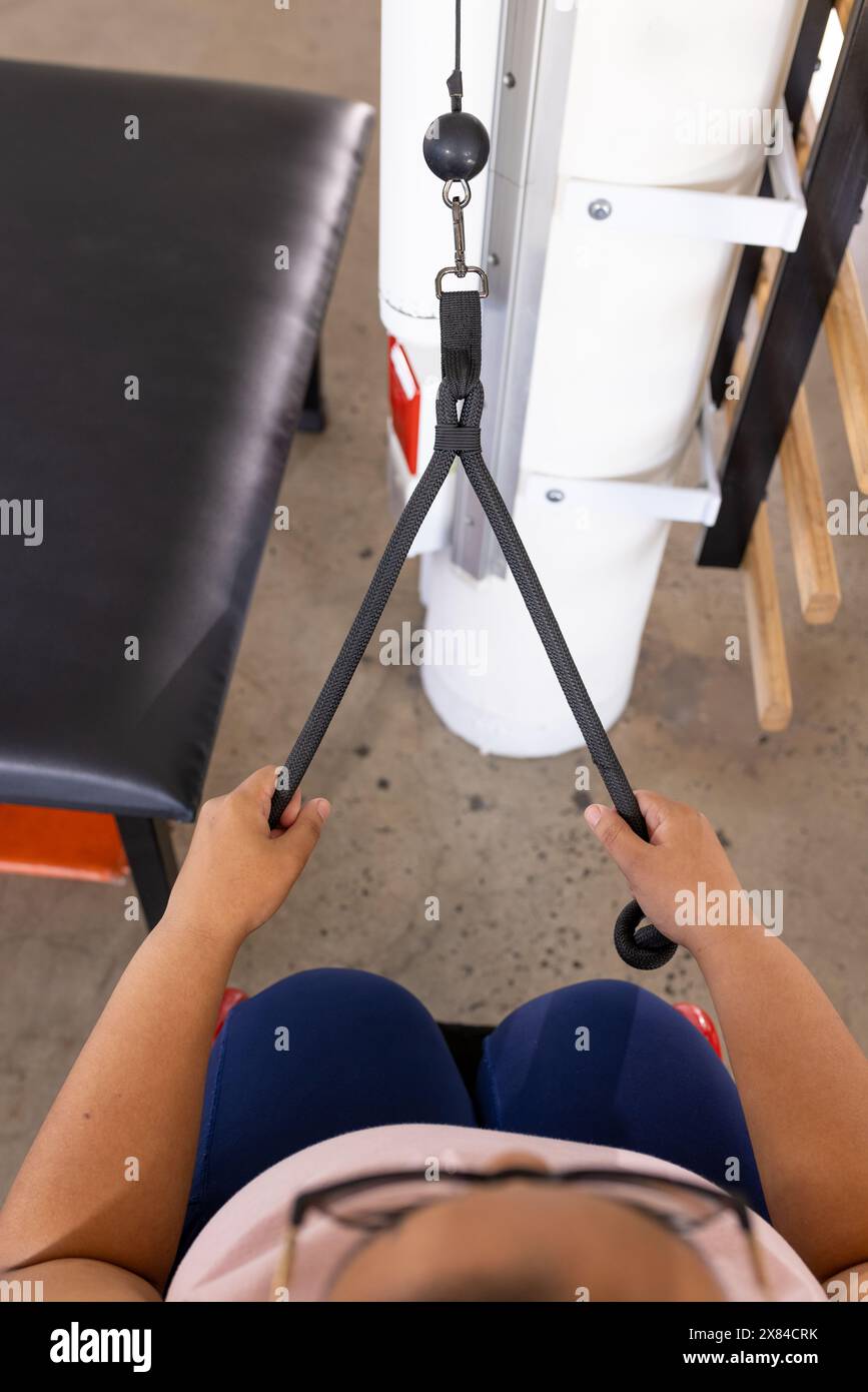 Entrainement de patiente paraplégique féminine biraciale avec équipement de gymnastique au centre de réadaptation Banque D'Images