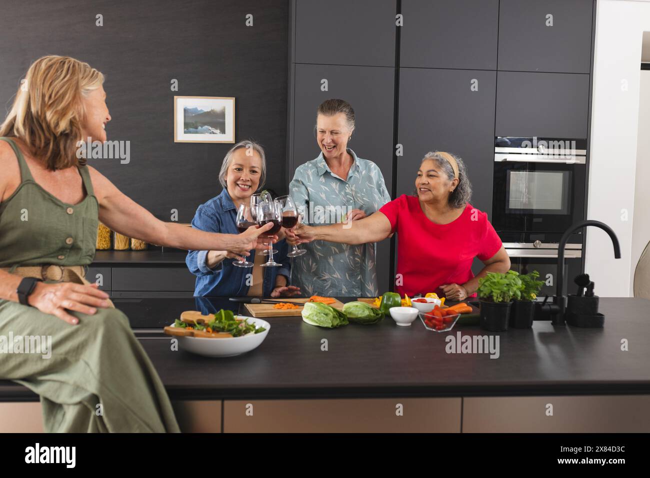 Diverses amies seniors appréciant des boissons à la maison dans la cuisine Banque D'Images