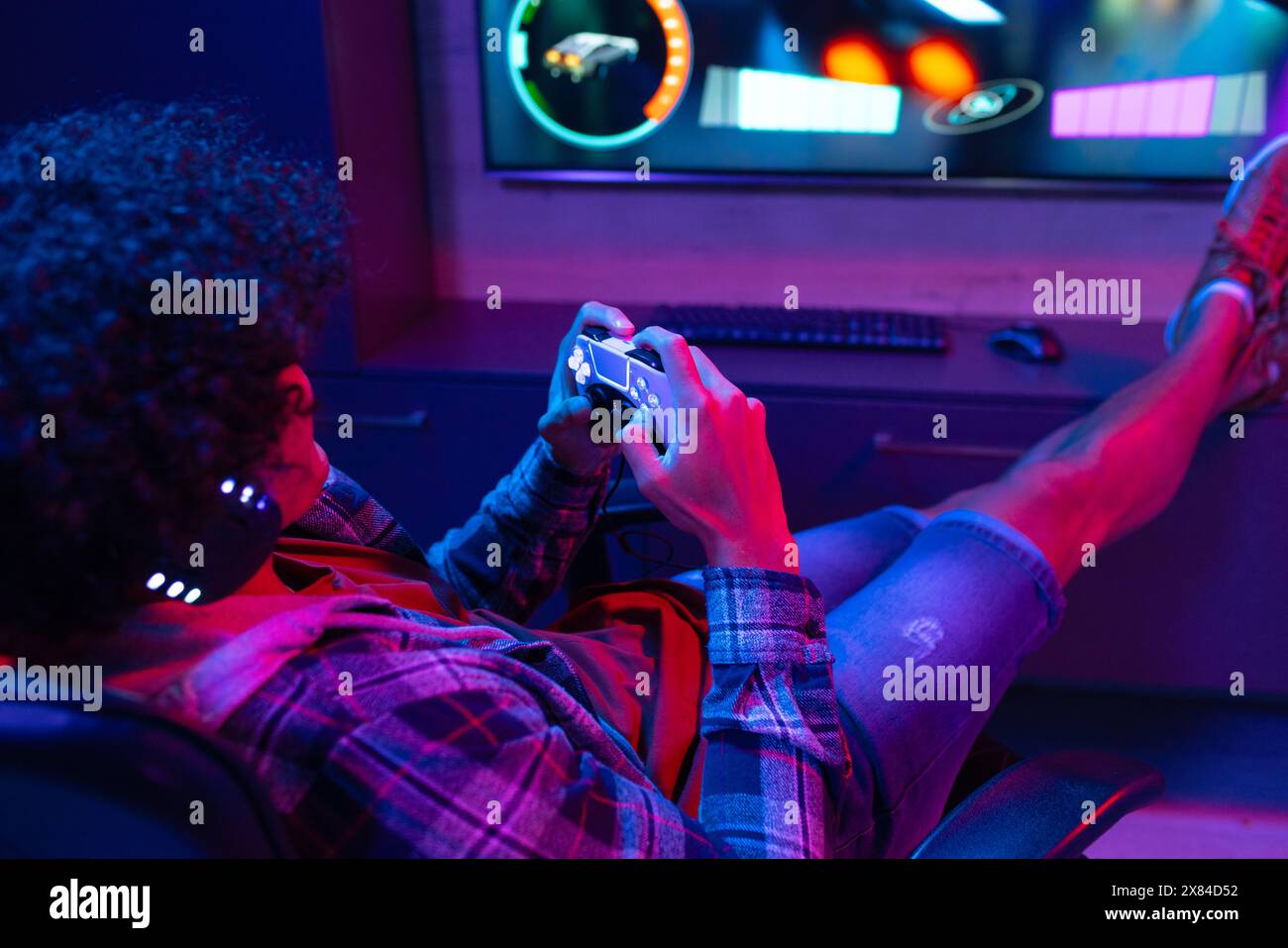 Un jeune homme biracial à la maison, portant des vêtements décontractés, jouant à des jeux vidéo Banque D'Images