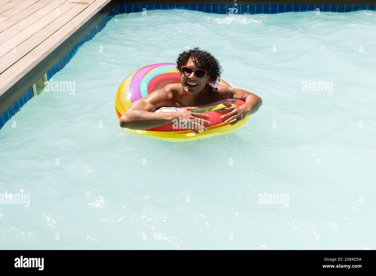 Un jeune homme biracial se relaxant à l'extérieur, tenant flotteur coloré, espace de copie Banque D'Images