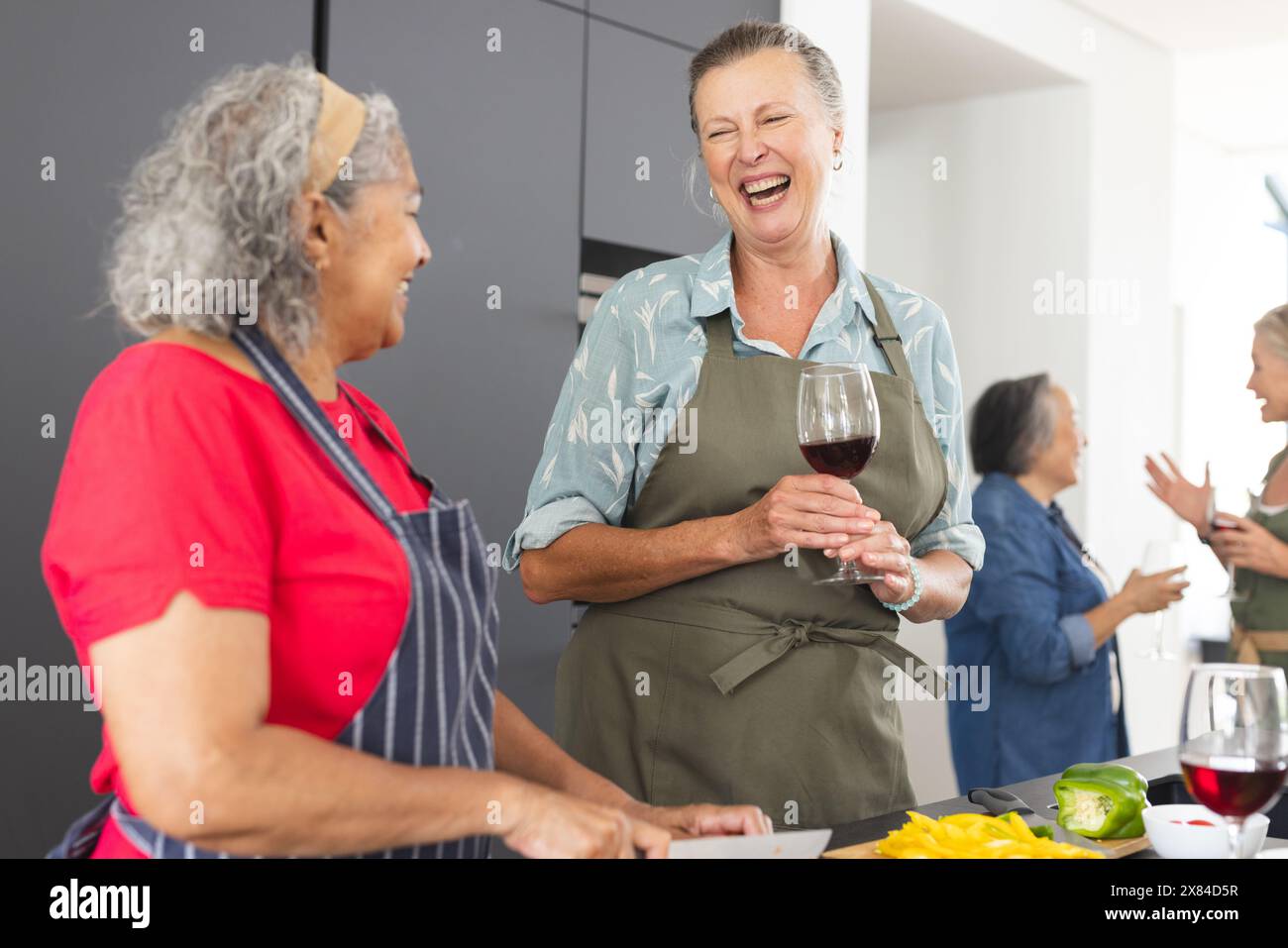 Diverses amies seniors riant, cuisinant à la maison Banque D'Images