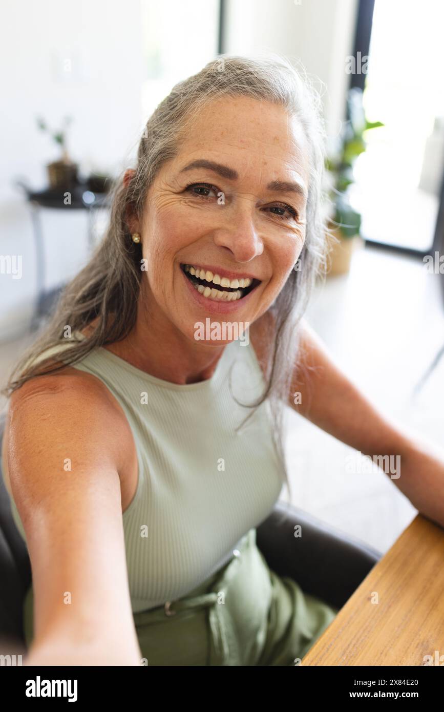 À la maison, femme caucasienne mature souriant pendant un appel vidéo Banque D'Images