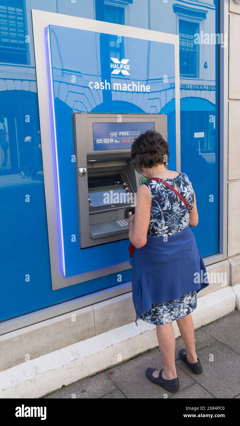 Femme retirant de l'argent d'un guichet automatique de Halifax à Leeds, West Yorkshire, Angleterre, Royaume-Uni Banque D'Images