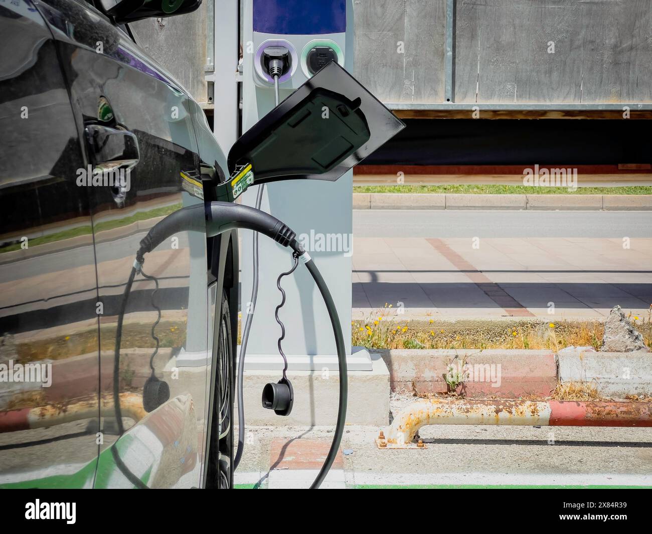 Une voiture électrique se recharge à la station de recharge de véhicule électrique dans le parking Banque D'Images