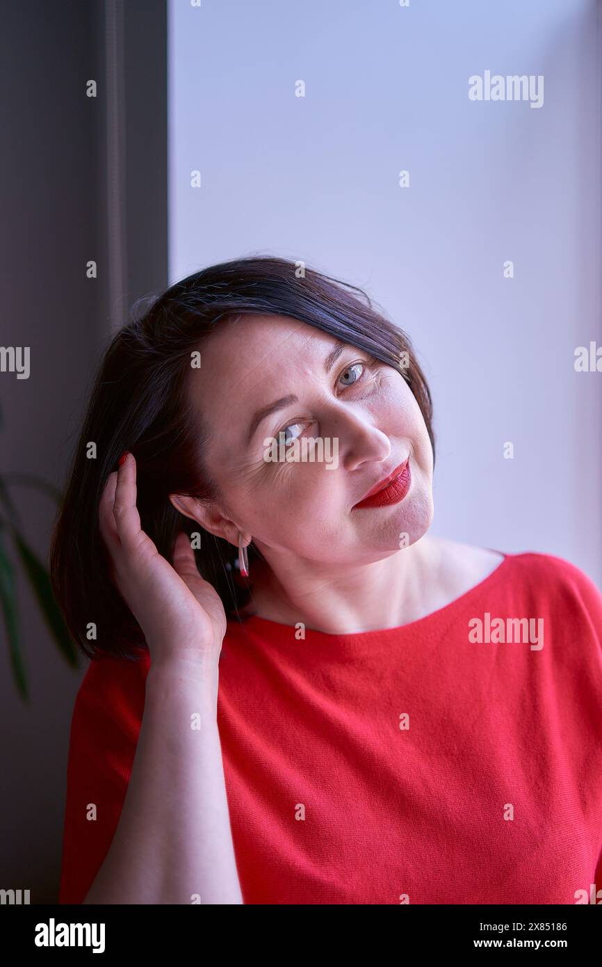 un portrait d'une brune avec une coupe de cheveux bob dans un pull rouge et une mini jupe en cuir au bureau Banque D'Images