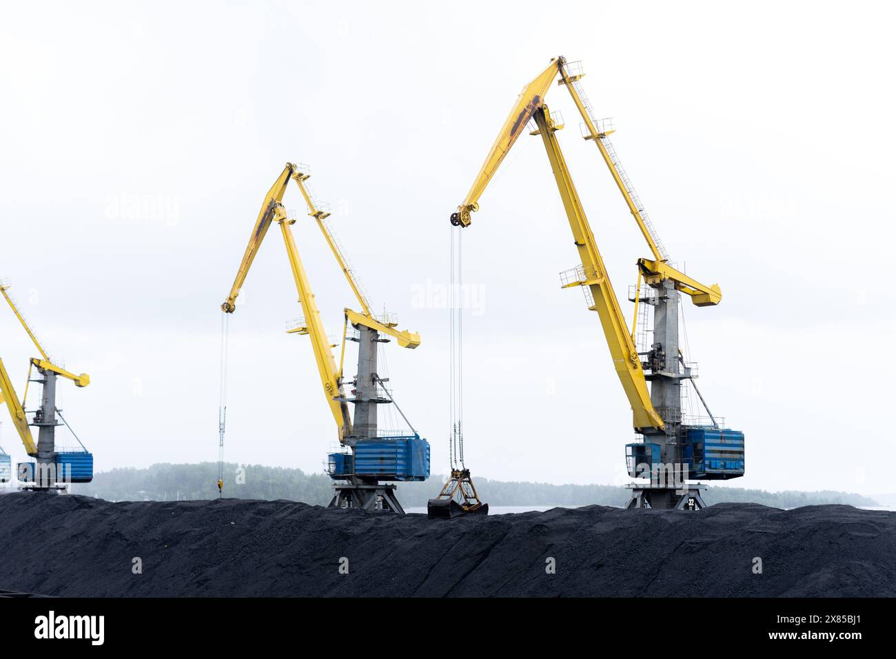 grues portuaires, grues portuaires industrielles pour port maritime avec stabilisateur et crochet contre un ciel bleu. Banque D'Images