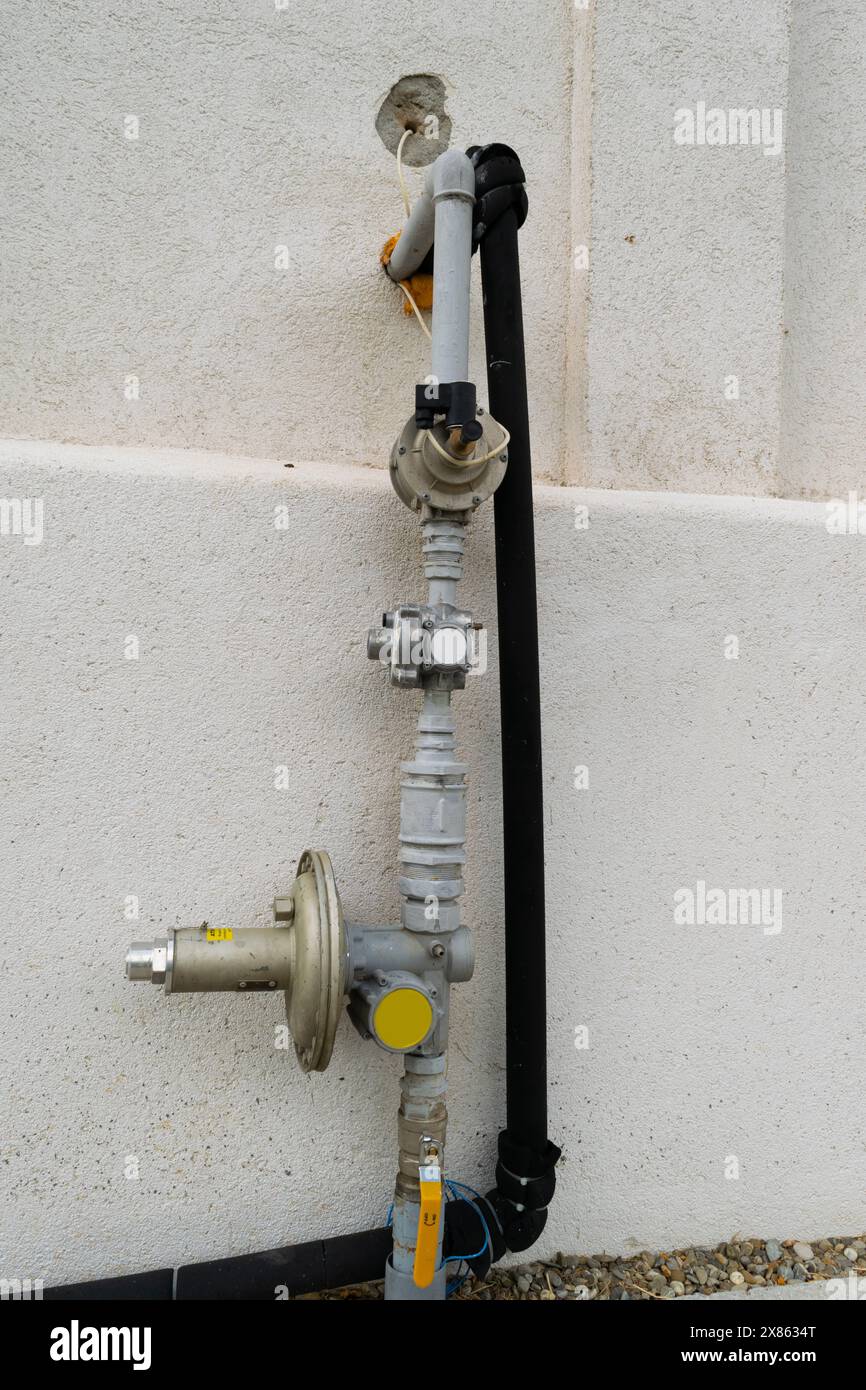 Gros plan d'un compteur de gaz extérieur avec des tuyaux et des vannes fixés à un mur de béton, utilisé pour la gestion des services publics. Banque D'Images