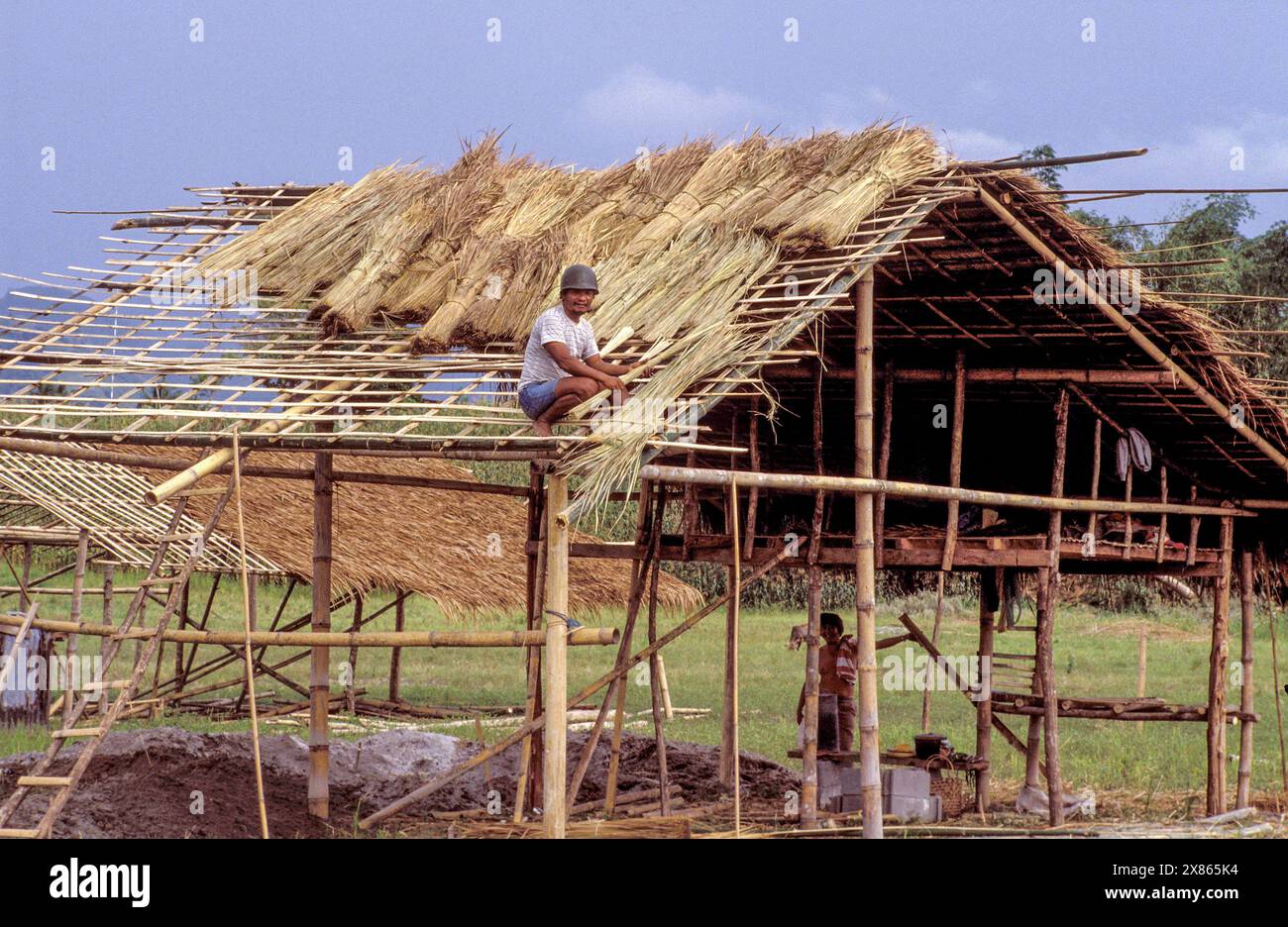 Philippines ; Luzon, Un homme est en train de creuser le toit de sa maison en bambou nouvellement construite. Banque D'Images