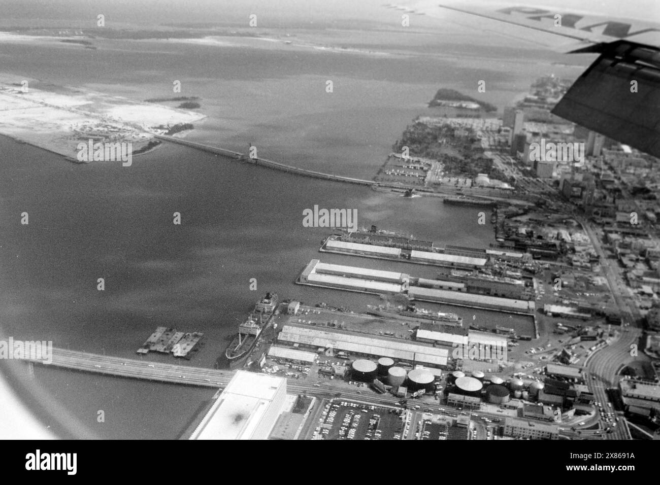 Blick auf den Hafen von Miami und die damals kaum bebaute künstlich angelegte Dodge Island in der Biscayne Bay aus dem Fenster einer Pan am Maschine, Floride 1966. Vue du port de Miami et de l'île artificielle à peine développée Dodge Island dans la baie de Biscayne depuis la fenêtre d'un avion Pan Am, Floride 1966. Banque D'Images