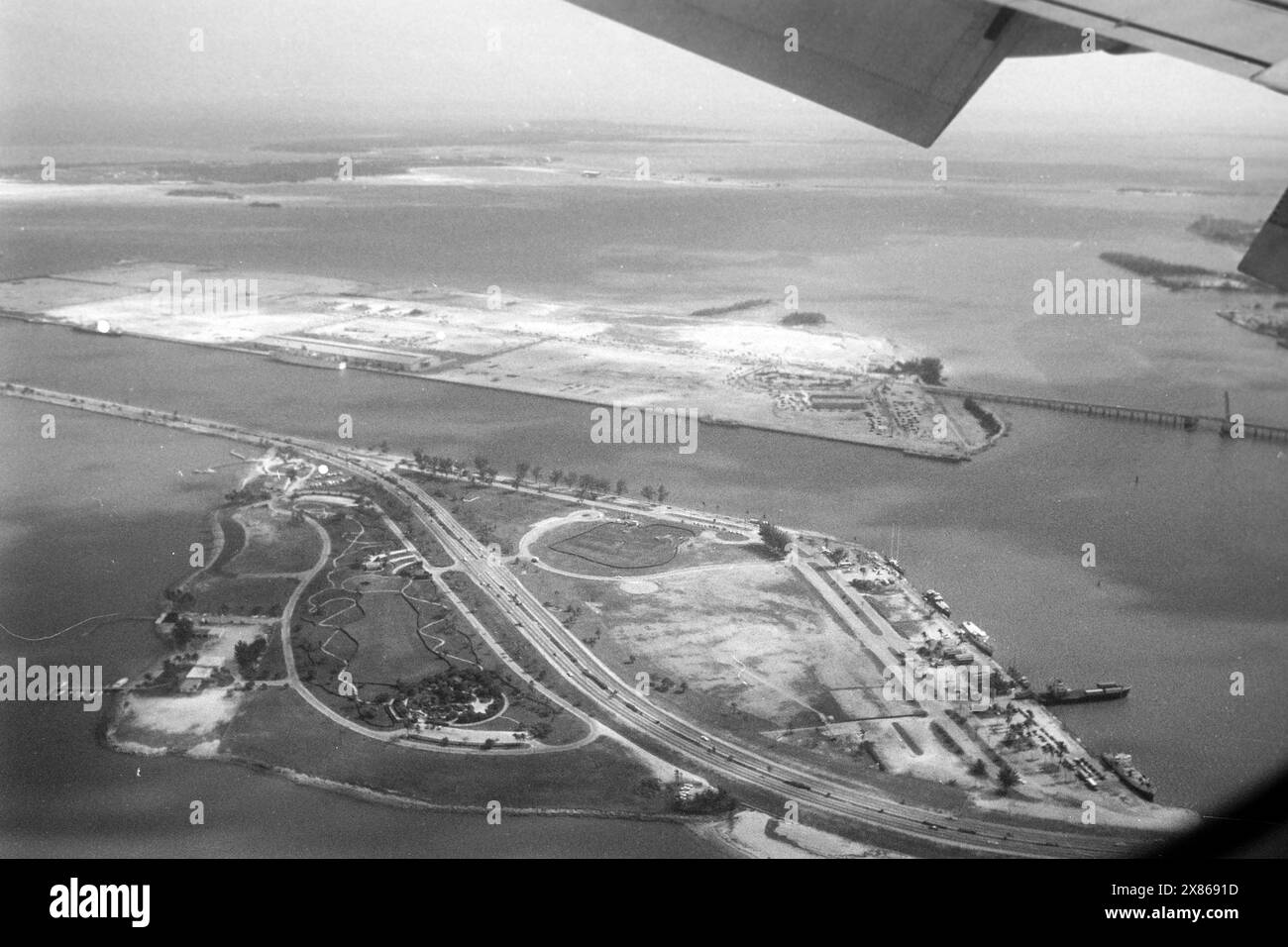 Blick auf die damals kaum bebauten künstlichen Inseln Watson Island und Dodge Island in der Biscayne Bay aus dem Fenster einer Pan am Maschine, Floride 1966. Vue des îles artificielles à peine développées de Watson Island et Dodge Island dans la baie de Biscayne depuis la fenêtre d'un avion Pan Am, Floride 1966. Banque D'Images