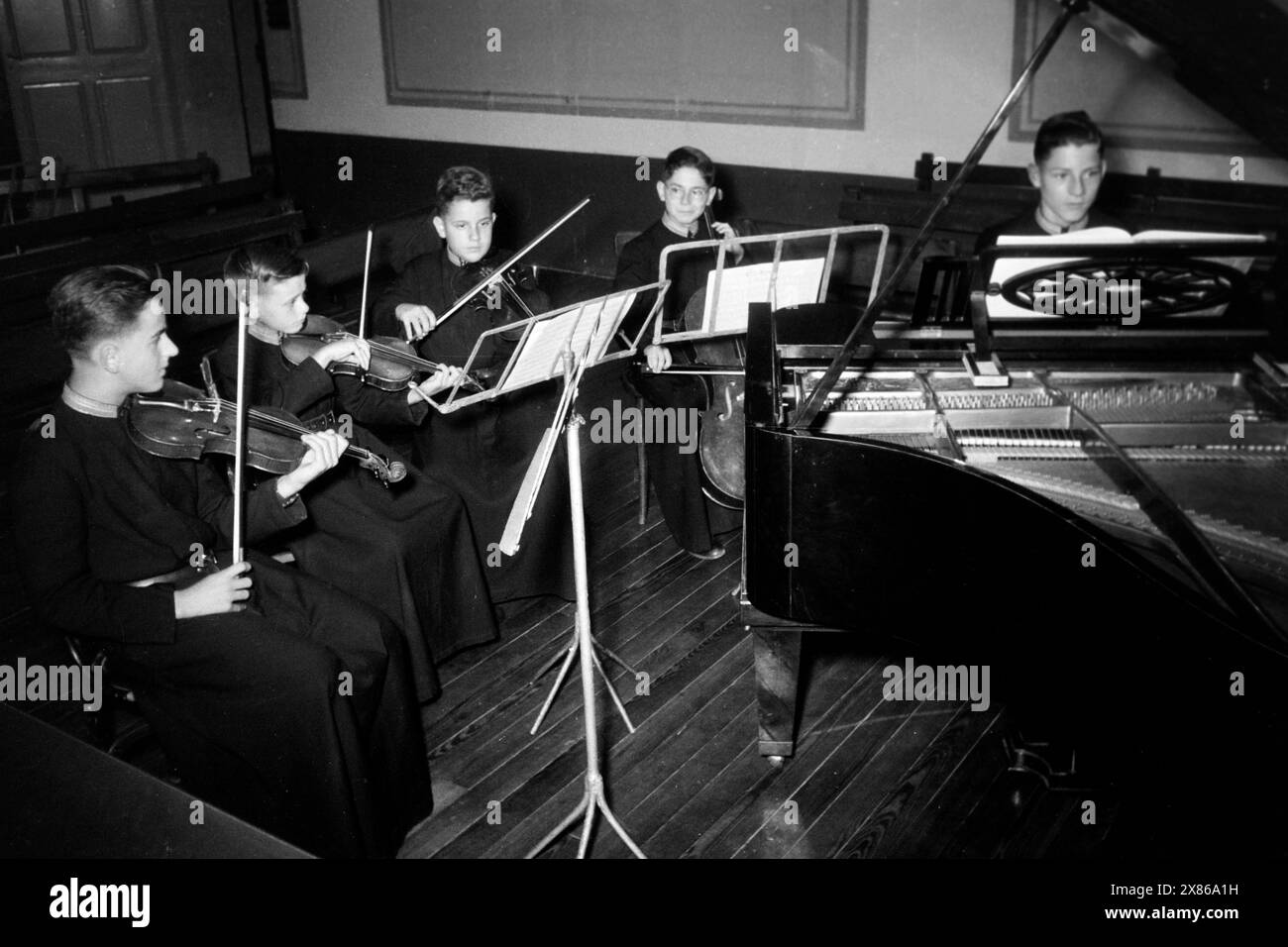 Schüler der Escolanía erhalten tiefgreifenden Musikunterricht und lernen neben dem Piano noch mindestens ein weiteres instrument wie Violine, Viola oder Cello, Katalonien 1957. Les élèves du Escolanía reçoivent des cours de musique approfondis et apprennent au moins un autre instrument en plus du piano, comme le violon, l'alto ou le violoncelle, Catalogne 1957. Banque D'Images
