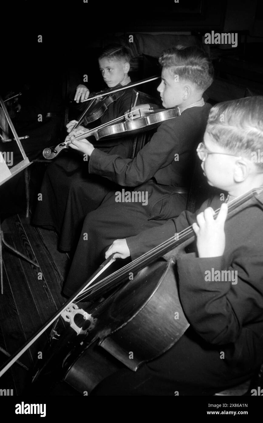 Schüler der Escolanía erhalten tiefgreifenden Musikunterricht und lernen neben dem Piano noch mindestens ein weiteres instrument wie Violine, Viola oder Cello, Katalonien 1957. Les élèves du Escolanía reçoivent des cours de musique approfondis et apprennent au moins un autre instrument en plus du piano, comme le violon, l'alto ou le violoncelle, Catalogne 1957. Banque D'Images