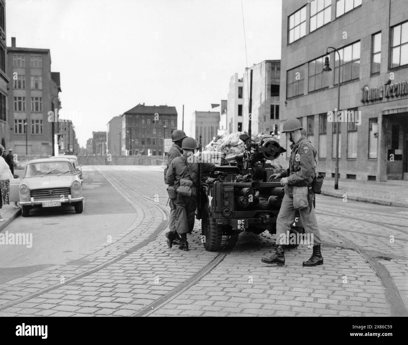 US-Soldaten Richten eine Kurzschusswaffe auf einem Jeep in Richtung der kürzlich errichtete Berliner Mauer aus, Berlin 1961. - Originale Bildbeschreibung : 'Mitten durch die Hauptstadt führt die Grenze der beiden Machtblöcke - OST : WEST - mit Betonmauern, Stacheldraht und - - - Bajonetten der Volkspolizei wächst die Mauer zwischen Ost und West, und zwar nicht nur in Berlin.' - Hanschriftlich ergänzt : Amerikaner in der Charlottenstr. Banque D'Images