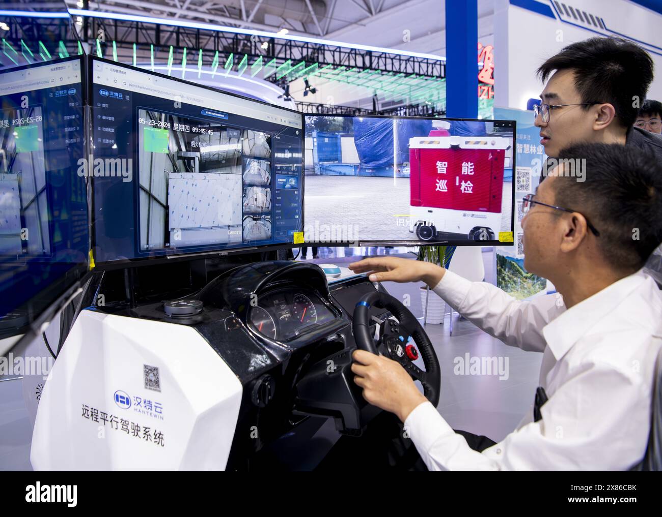 Fuzhou, province chinoise du Fujian. 23 mai 2024. Un visiteur (R) essaie le système de conduite parallèle à distance dans la zone d'expérience sur site pour le 7e Sommet de la Chine numérique à Fuzhou, dans la province du Fujian, au sud-est de la Chine, le 23 mai 2024. Le 7e Digital China Summit aura lieu à Fuzhou du 24 au 25 mai. L'avant-première de sa zone d'expérience sur place, couvrant une superficie de 56 000 mètres carrés et composé de cinq parties principales, a été ouverte au Centre international de conférence et d'exposition du détroit de Fuzhou jeudi. Crédit : Wei Peiquan/Xinhua/Alamy Live News Banque D'Images