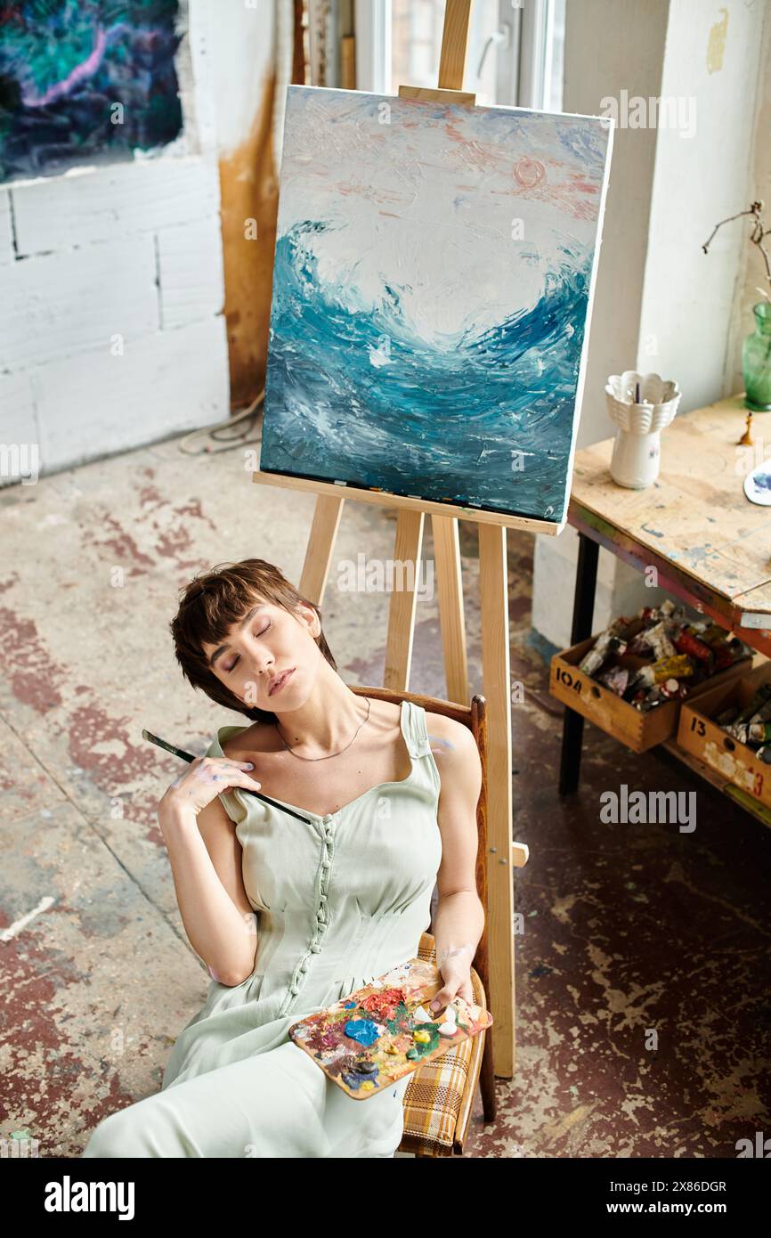 La femme est assise devant la peinture. Banque D'Images