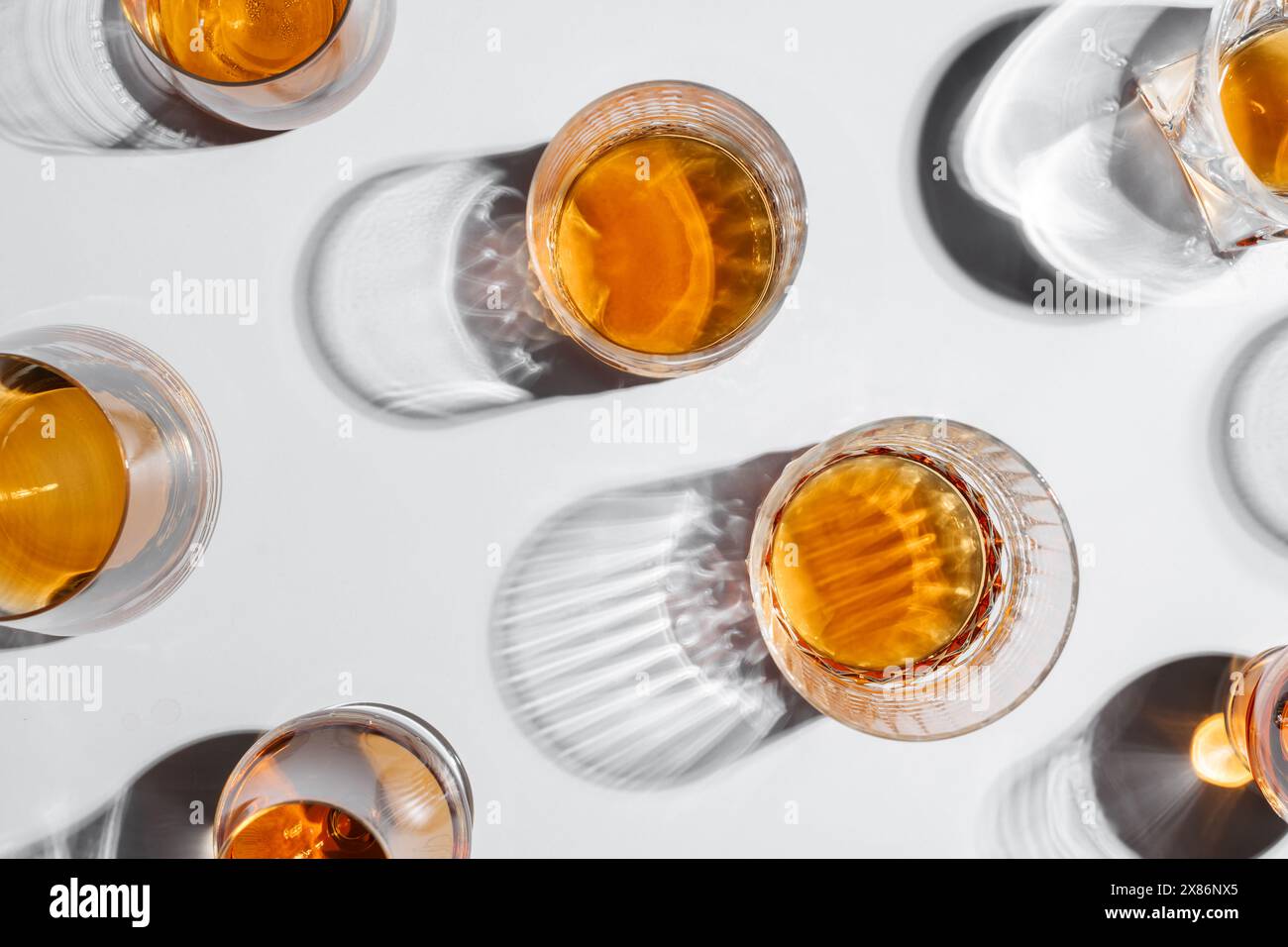 Vue de dessus de verres de forme différente avec whisky avec ombre sur la table blanche. Concept d'alcool Banque D'Images