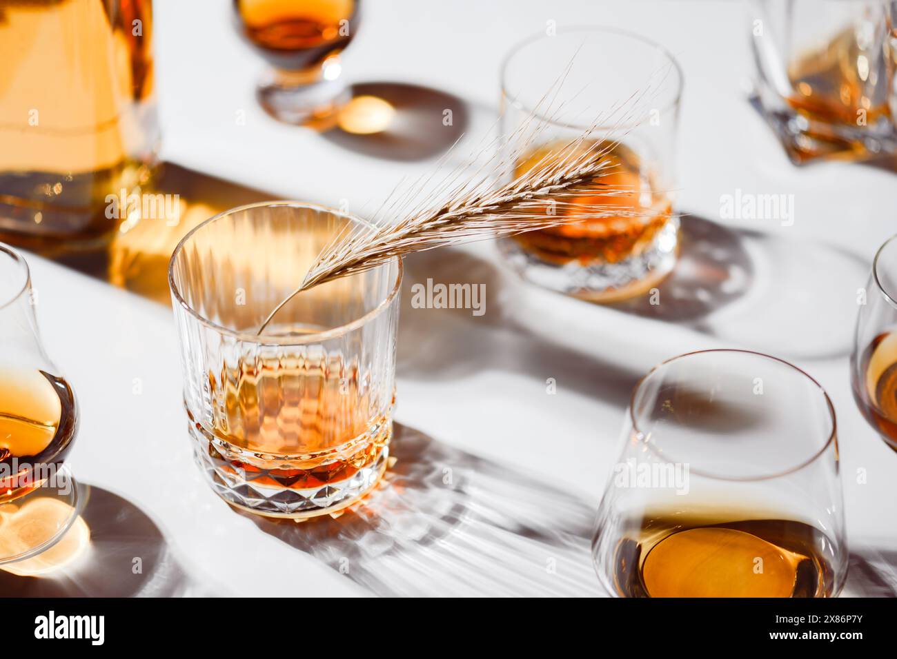 Verres de forme différente avec whisky sur table blanche. Décoration de pointe d'orge séchée. Concept d'alcool Banque D'Images