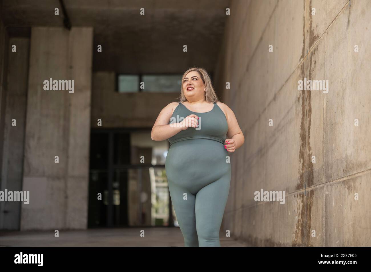 Heureuse femme sinueuse courant près du mur Banque D'Images