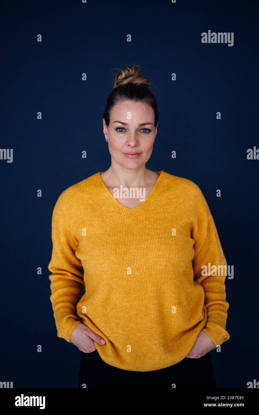 Belle femme confiante debout avec les mains dans les poches sur fond coloré Banque D'Images